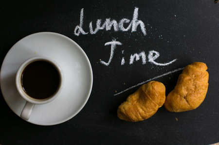 Cup of black coffee and croissants on the chalkboard with noteの写真素材