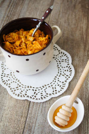 nutritious cereal cornflakes breakfast on the wooden table with honey and milk