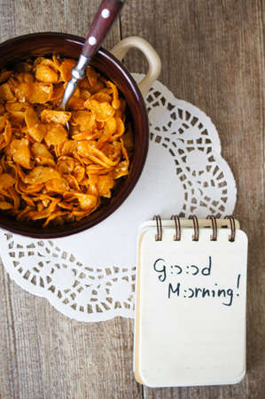 nutritious cereal cornflakes breakfast on the wooden table with good morning noteの写真素材