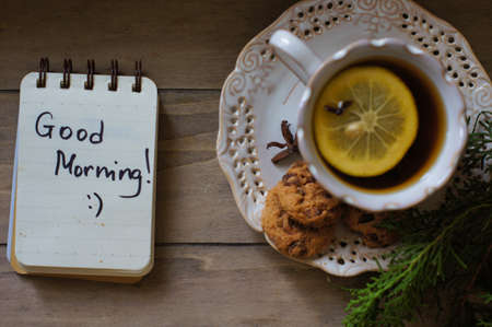 Cup of tea with lemon and cookies on the table with Good morning noteの写真素材