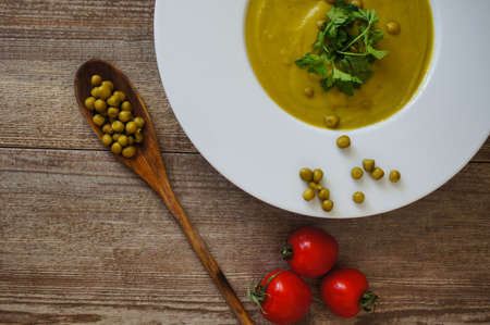 Fresh green pea soup with pea seeds and pea pods around. Selective Focusの写真素材