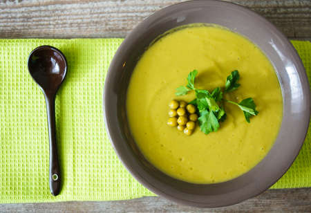 Fresh green pea soup with pea seeds and pea pods around. Selective Focusの写真素材