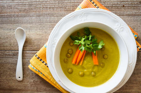 Fresh green pea soup with pea seeds and pea pods around. Selective Focusの写真素材