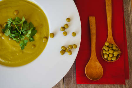 Fresh green pea soup with pea seeds and pea pods around. Selective Focusの写真素材
