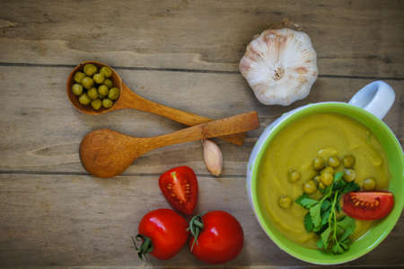 Fresh green pea soup with pea seeds and pea pods around. Selective Focusの写真素材