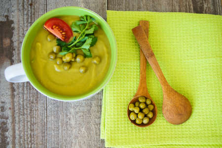 Fresh green pea soup with pea seeds and pea pods around. Selective Focusの写真素材