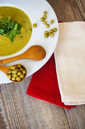Fresh green pea soup with pea seeds and pea pods around. Selective Focusの写真素材