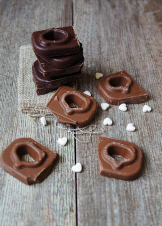 Heart-shaped pieces of chocolate and spices on the wooden background