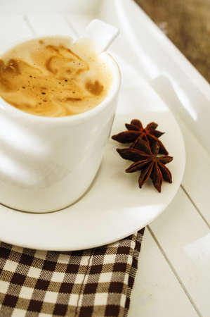 Cup of coffee with anise spices on the wooden tableの写真素材