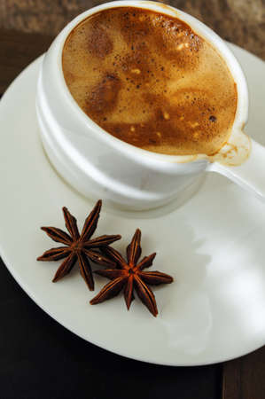 Cup of coffee with anise spices on the wooden tableの写真素材