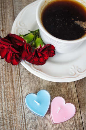 Cup of tea, red cloves flowers and heart shaped candles