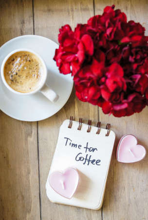 Cup of coffee and red cloves flowers in a vase with good morning note