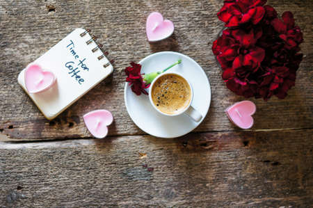 Cup of coffee and red cloves flowers in a vase with good morning noteの写真素材