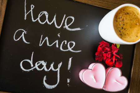 Cup of coffee and red cloves flowers in a vase with good morning noteの写真素材