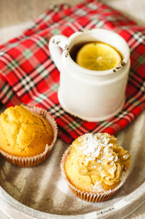 Sweet muffins and cup of black tea on the table with napkinの写真素材