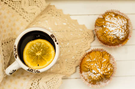 Sweet muffins and cup of black tea on the table with napkinの写真素材