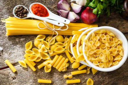 Different kinds of italian pasta, like a fusilli, farfalle, spaghetti and penne pastaの写真素材