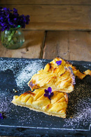 French apple tart on the old rustic table with flowers and napkinの写真素材
