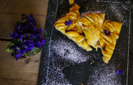 French apple tart on the old rustic table with flowers and napkinの写真素材