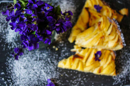 French apple tart on the old rustic table with flowers and napkinの写真素材