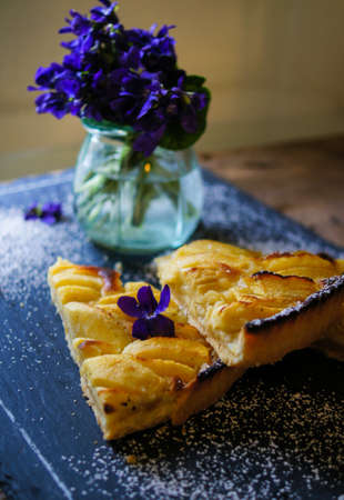 French apple tart on the old rustic table with flowers and napkinの写真素材