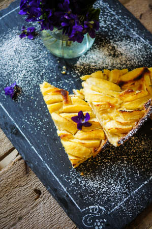 French apple tart on the old rustic table with flowers and napkinの写真素材