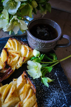 French apple tart on the old rustic table with flowers and napkinの写真素材