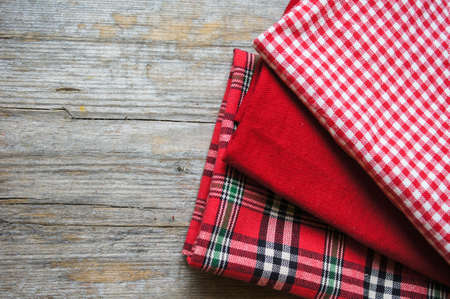 Stack of colorful dish towels on wooden table.