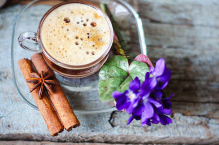 First spring flowers of violets and cup of coffee on the old wooden tableの写真素材