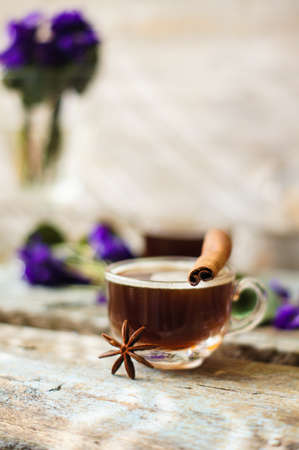 First spring flowers of violets and cup of coffee on the old wooden table