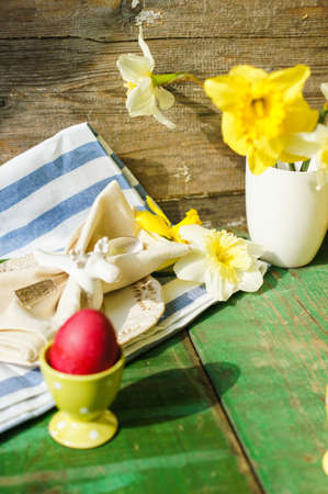 Spring festive easter dining table setting with yellow daffodil flowers,  napkins and vintage...