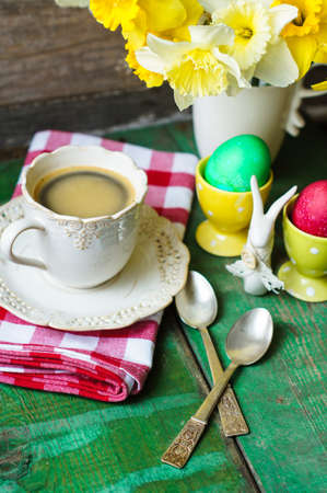 Cup of coffee, easter eggs and bunny on the old wooden tableの写真素材