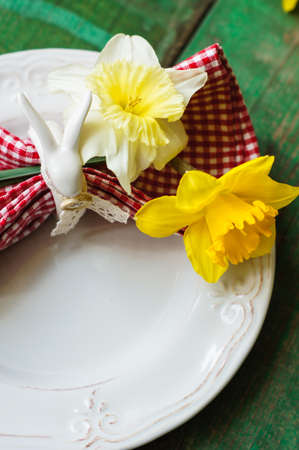 Spring festive easter dining table setting with yellow daffodil flowers,  napkins and vintage cutlery on a wooden boardの写真素材