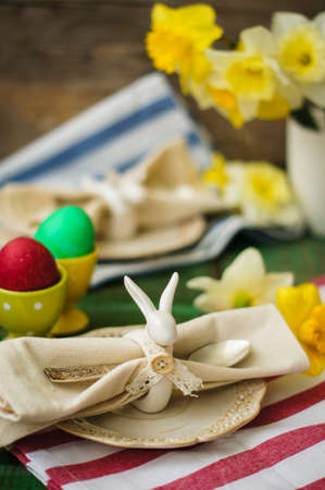 Spring festive easter dining table setting with yellow daffodil flowers,  napkins and vintage...