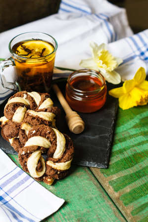 Cup of tea with cookies on the bright napkin, a mug with honey and daffodil flowersの写真素材