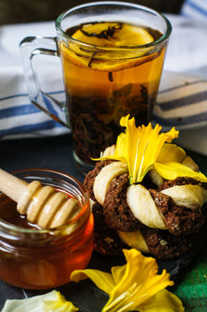 Cup of tea with cookies on the bright napkin, a mug with honey and daffodil flowersの写真素材