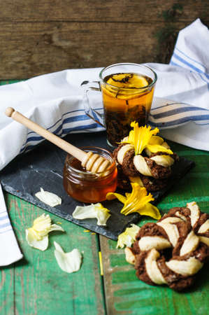 Cup of tea with cookies on the bright napkin, a mug with honey and daffodil flowersの写真素材