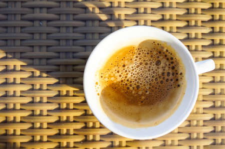 Cup of coffee on the table on the beach in sunlightの写真素材