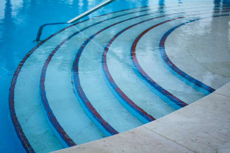 blue swimming pool with teak wood flooring stripes summer vacationの写真素材