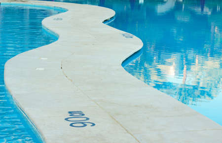 blue swimming pool with teak wood flooring stripes summer vacationの写真素材
