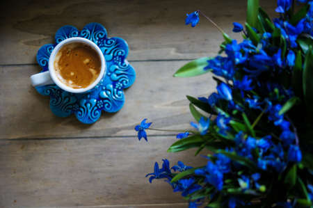 scilla siberica flowers in a vase and cup of coffee in rustic interiorの写真素材