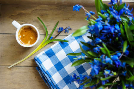 scilla siberica flowers in a vase and cup of coffee in rustic interiorの写真素材