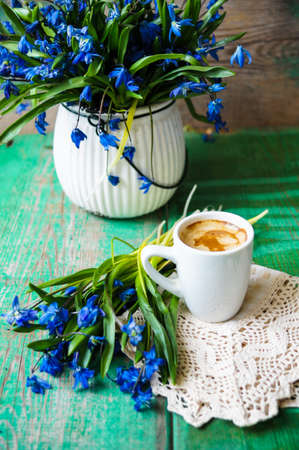 scilla siberica flowers in a vase and cup of coffee in rustic interiorの写真素材