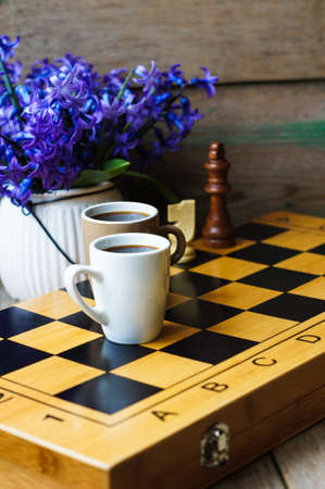 Cup of coffee on the chess board and first spring flowers Scyllaの写真素材