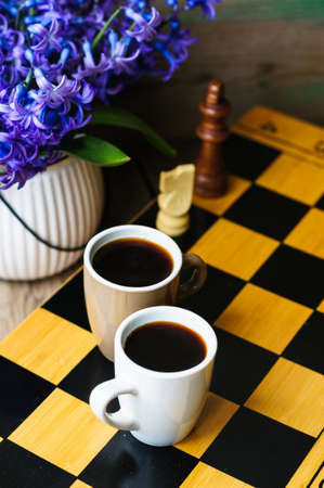 Cup of coffee on the chess board and first spring flowers Scyllaの写真素材