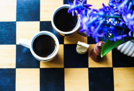 Cup of coffee on the chess board and first spring flowers Scyllaの写真素材