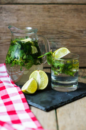 Lemonade with fresh mint, lime and lemon on the rustic kitchen
