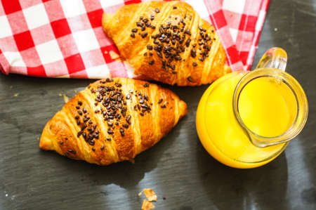Breakfast, orange juice and fresh chocolate criossants on the tableの写真素材