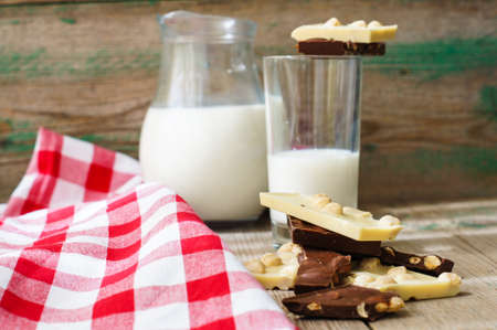 Glass of milk and bars of two types of chocolateの写真素材