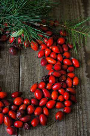 Christmas time decoration with rose hips  and branch of christmas tree on the wooden backgroundの写真素材